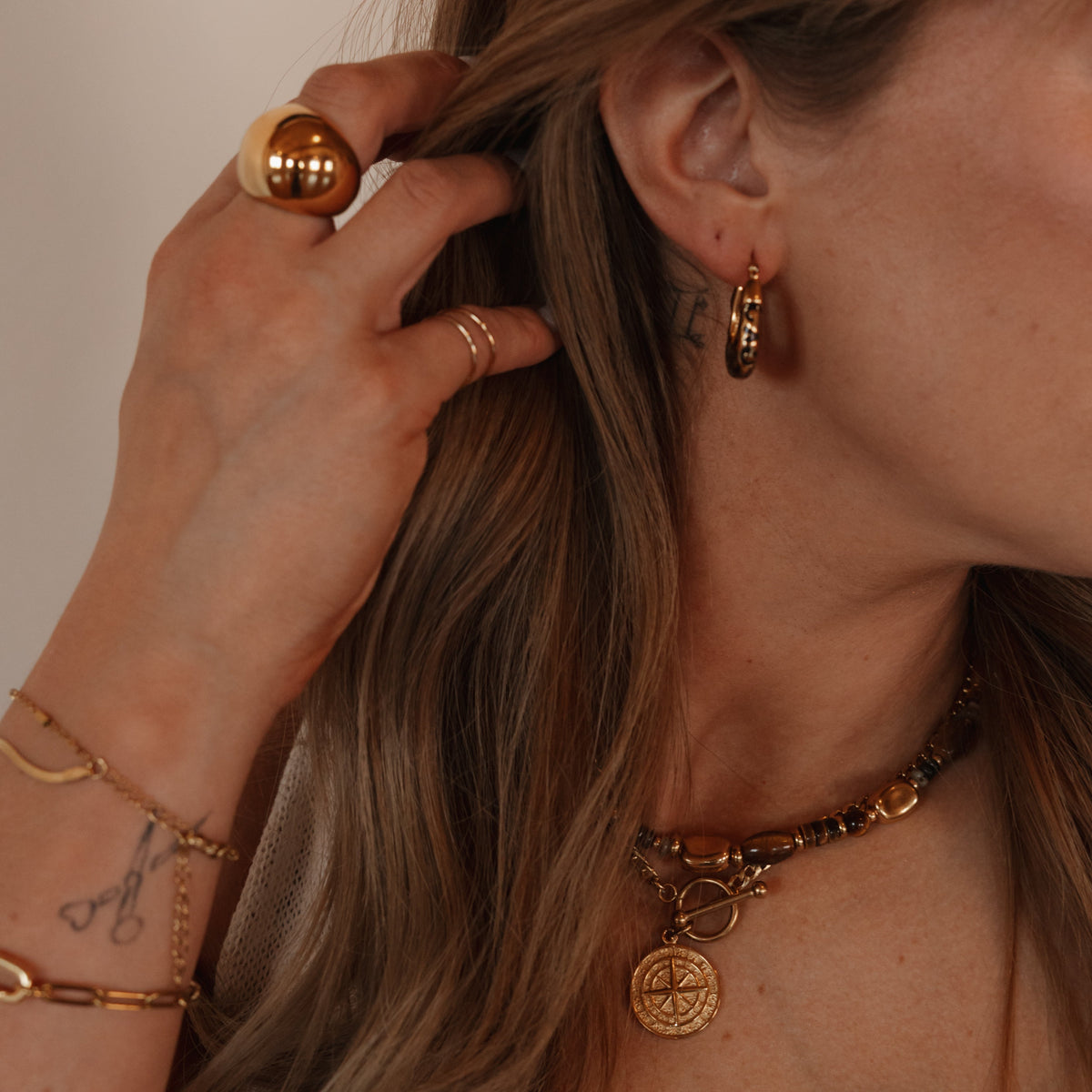 Sarah gold compass necklace layered with chunky tiger eye necklace