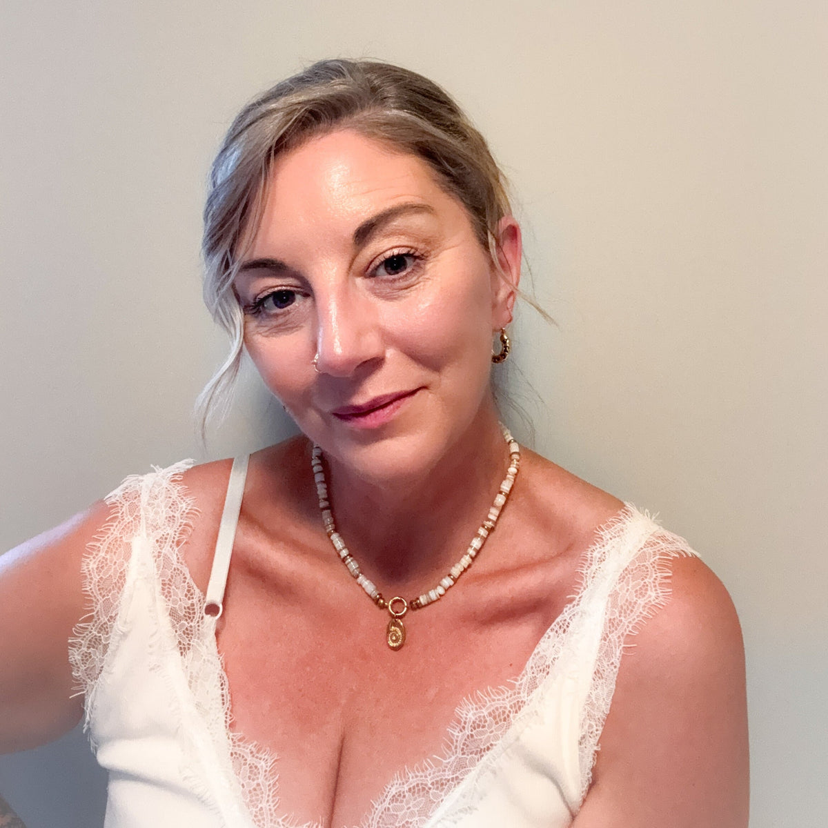 Woman wearing the Sunday Shell Necklace with creamy shell beads, gold accents and shell charm