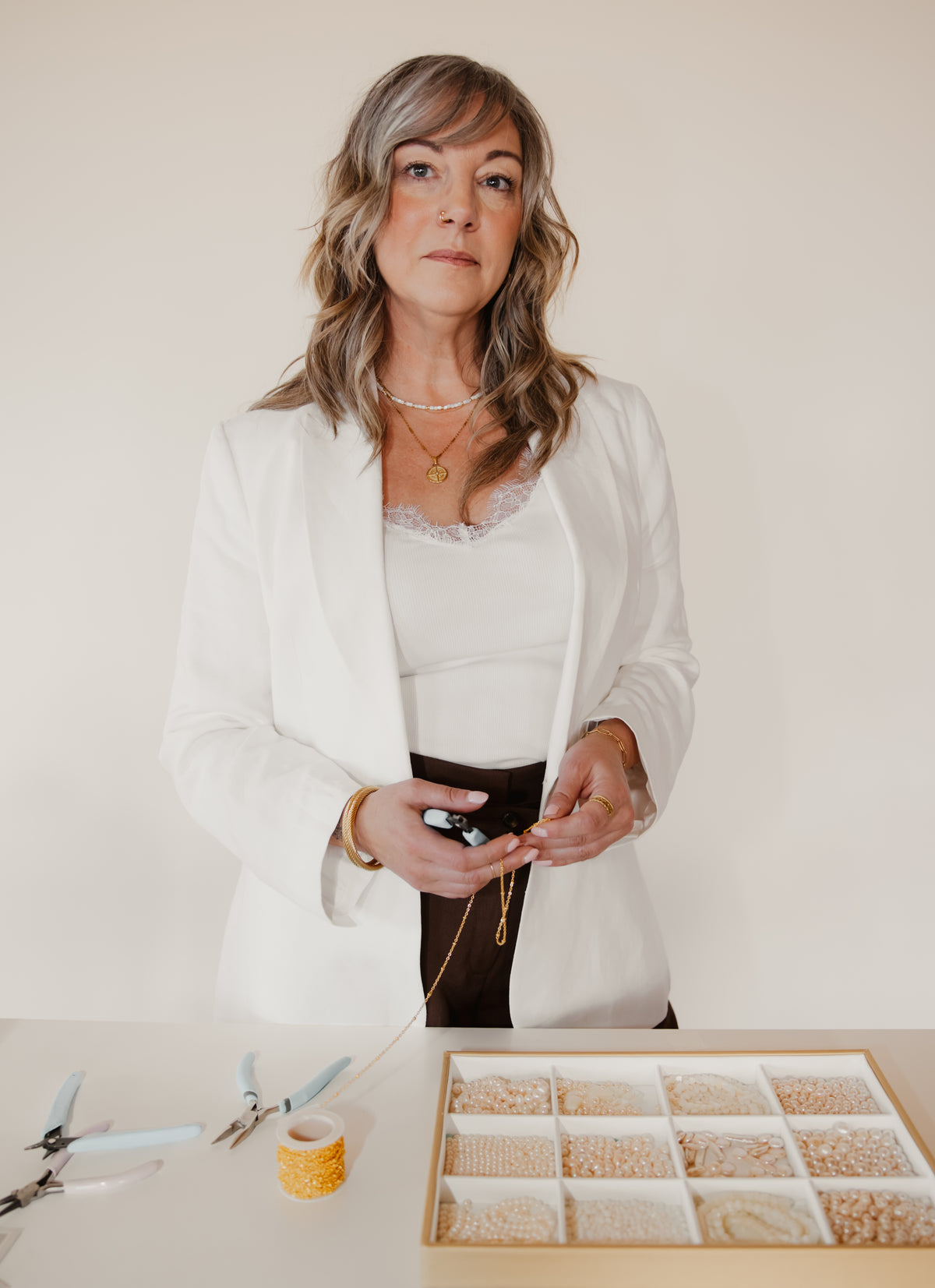 Woman wearing the delicate Little Things shell and gold beaded necklace while making jewelry