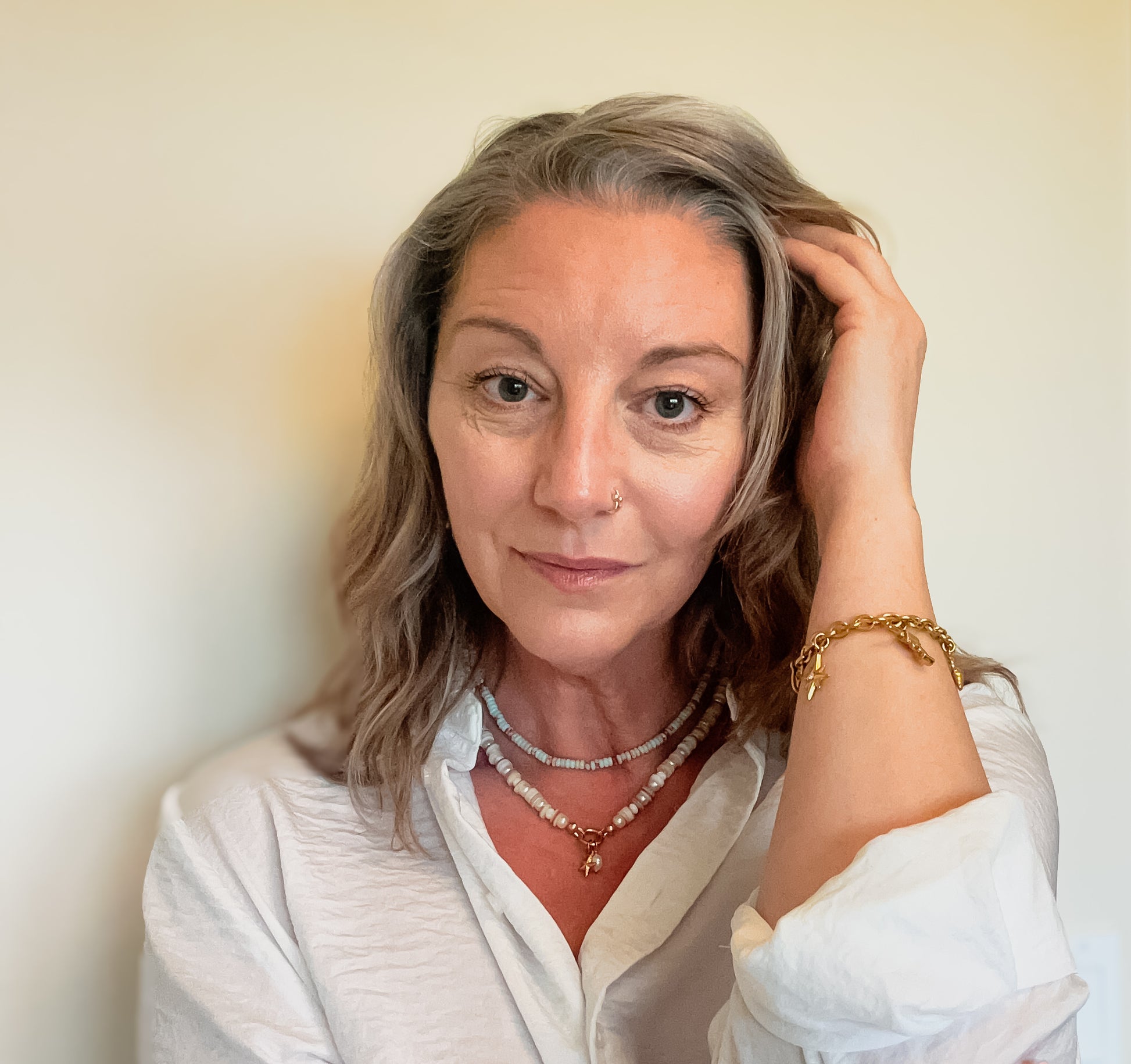 woman wearing beach inspired shell necklaces and golden western charm bracelet, meaningful jewelry that gives back to mental health awareness