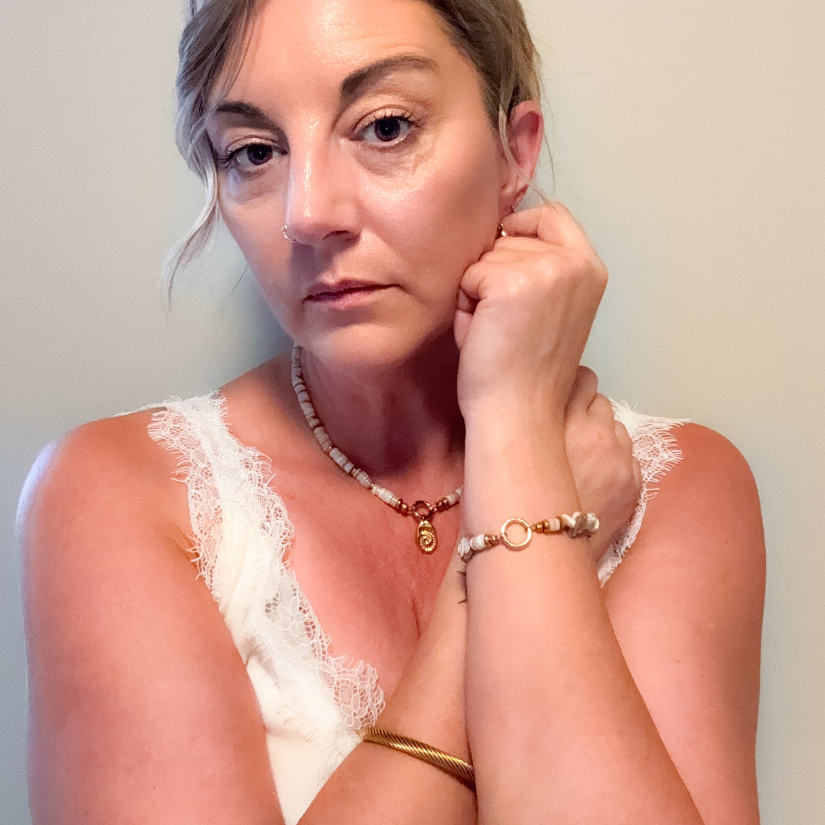Woman wearing the Sunday Shell Necklace with creamy shell beads, gold accents and shell charm