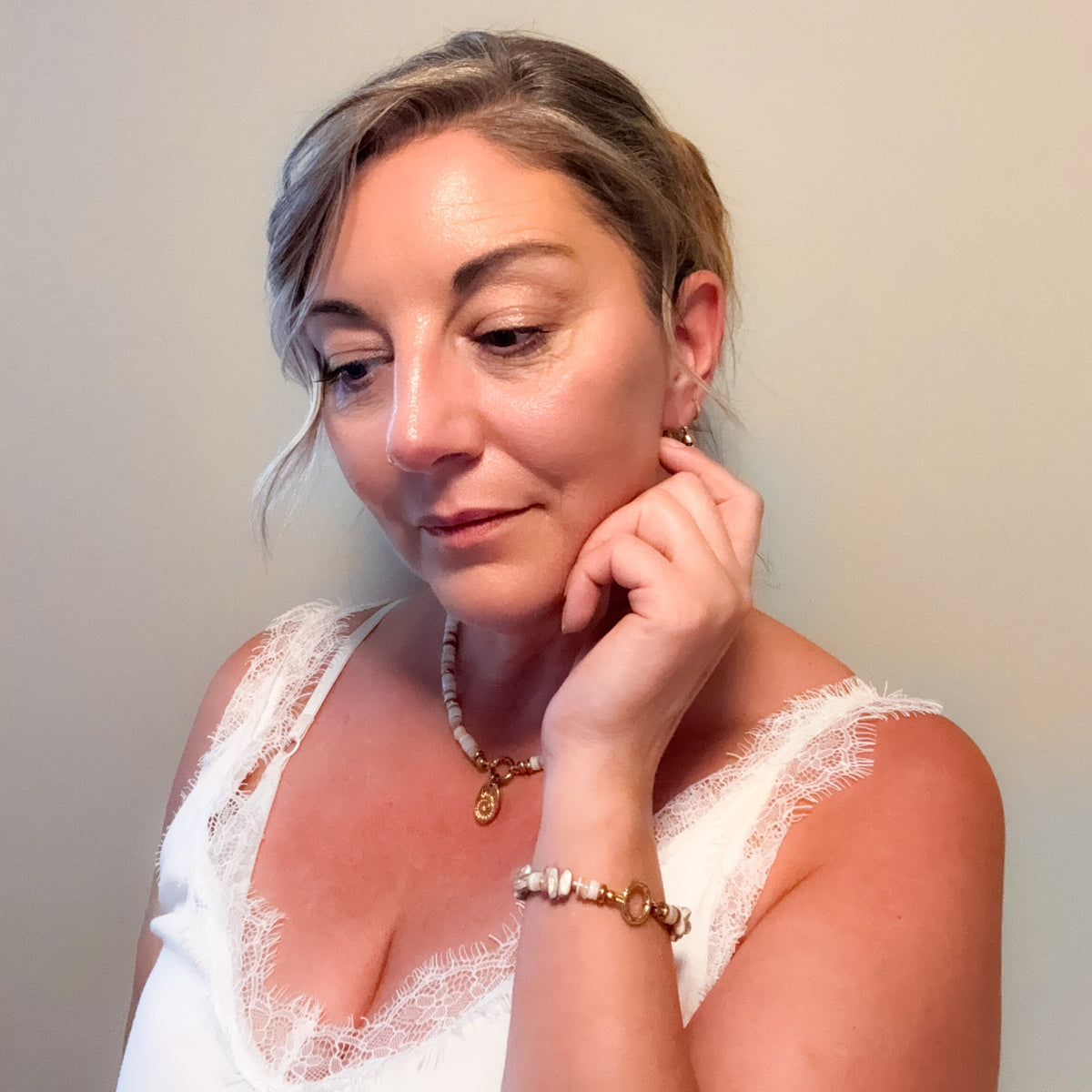 Woman wearing the Sunday Shell Necklace with creamy shell beads, gold accents and shell charm