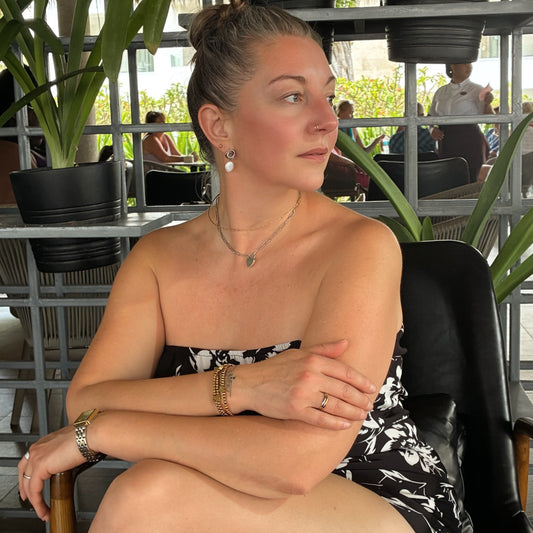 woman in chair wearing silver knot earring with freshwater pearl. Isla Rae jewelry- Canada