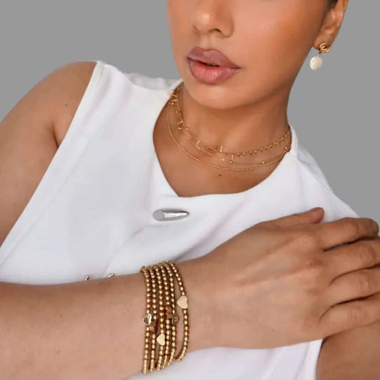 woman wearing gold beaded bracelet with heart, handmade by isla rae jewlery in canada 