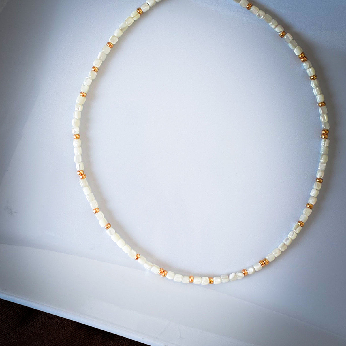 Close-up of tiny creamy shell beads and gold accents on the Little Things Necklace