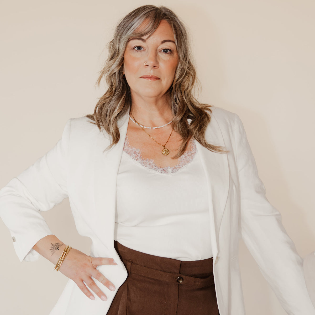 Woman wearing the delicate Little Things shell and gold beaded necklace, layered with gold compass necklace